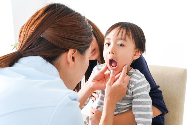 口を開ける男の子と口内を見る女性歯科スタッフ
